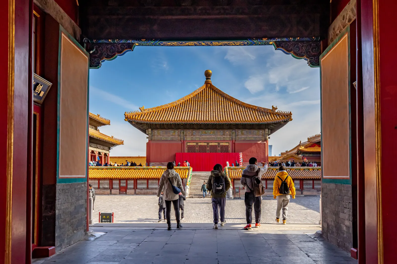 Visitors walking through a doorway towards palace halls in the Forbidden City